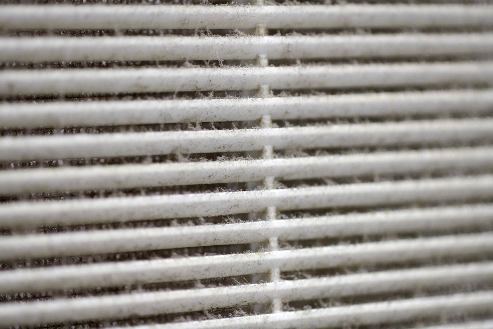 Close-up of a dusty air vent grill with accumulated dirt and debris on the slats.